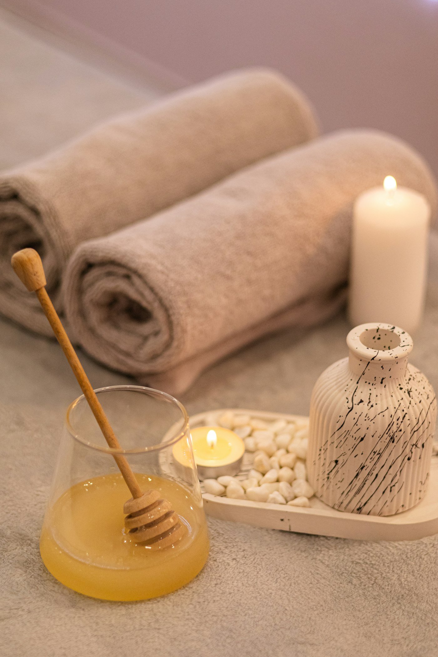 Rolled towels, candle and honey